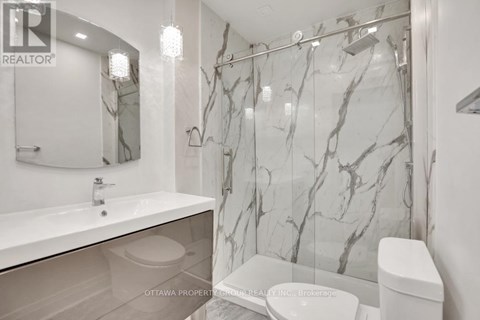 A bathroom with marble wallpaper and a glass shower door.