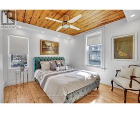 A bedroom with a bed, a chair, and a painting on the wall.