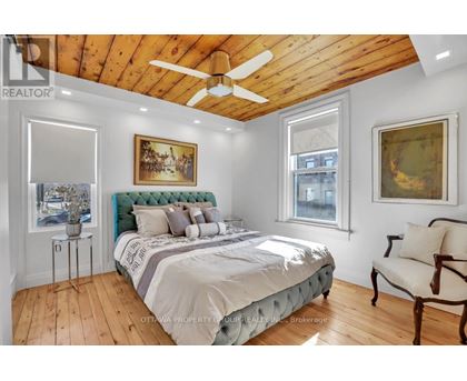 A bedroom with a bed, a chair, and a painting on the wall.