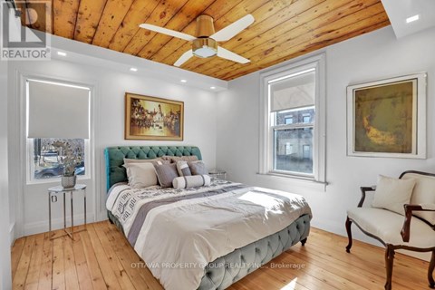 A bedroom with a bed, a chair, and a painting on the wall.