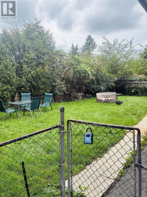 A backyard with a fence and a table and chairs.
