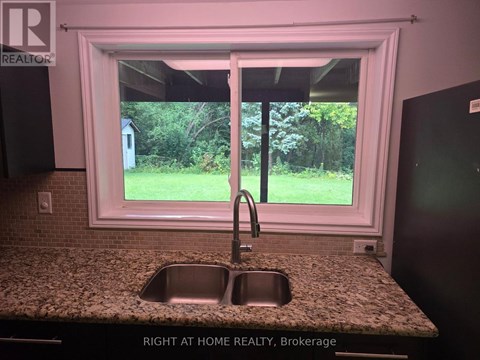 A kitchen with a granite countertop and a sink under a window.