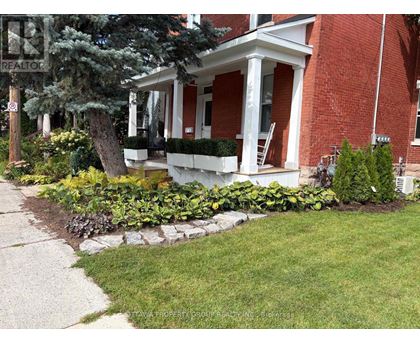 A red brick house with a white porch and a sign that says REALTOR.