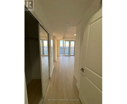 A hallway with wooden floors and white walls leading to a door.