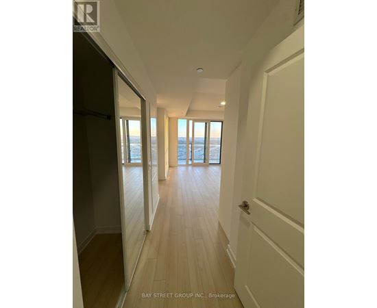 A hallway with wooden floors and white walls leading to a door.