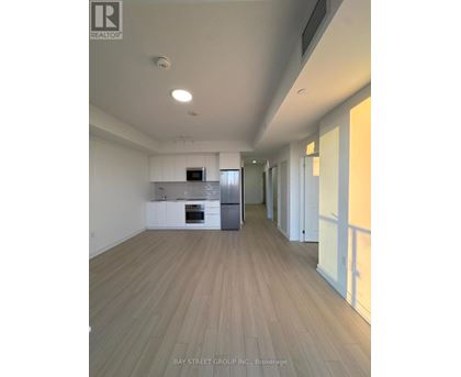 A spacious kitchen with white cabinets and a wooden floor.