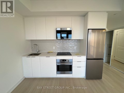 A modern kitchen with white cabinets and stainless steel appliances.