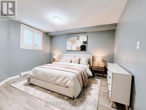 A bedroom with a large bed and a nightstand with a lamp.