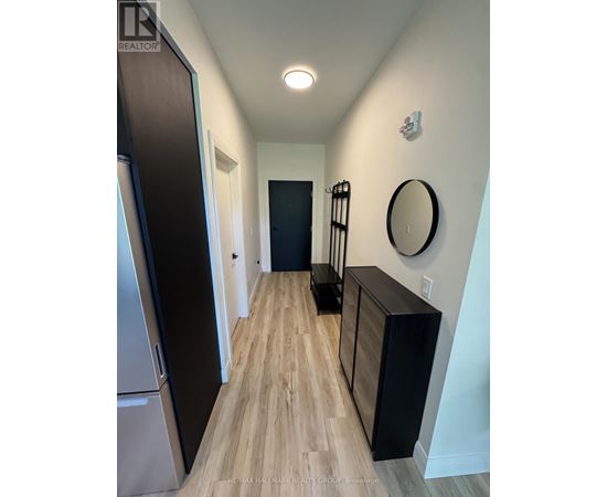 A hallway with a wooden floor and a black door.
