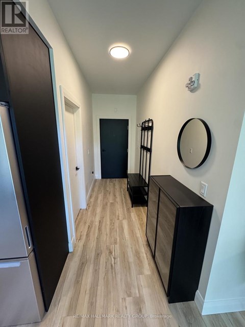 A hallway with a wooden floor and a black door.
