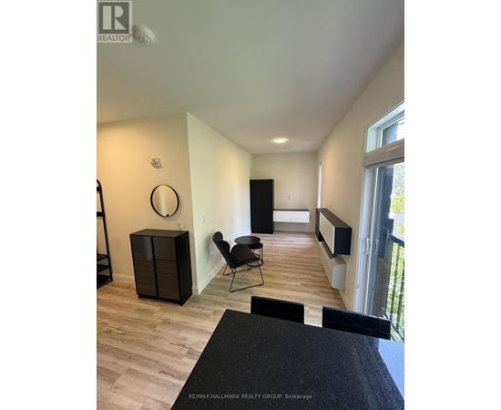 A black chair is in a white room with wood flooring.