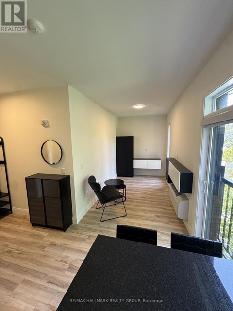A black chair is in a white room with wood flooring.