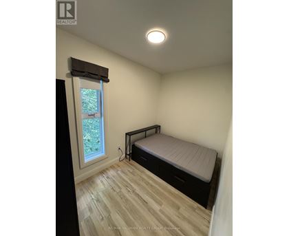 A bedroom with a bed, window, and wooden flooring.