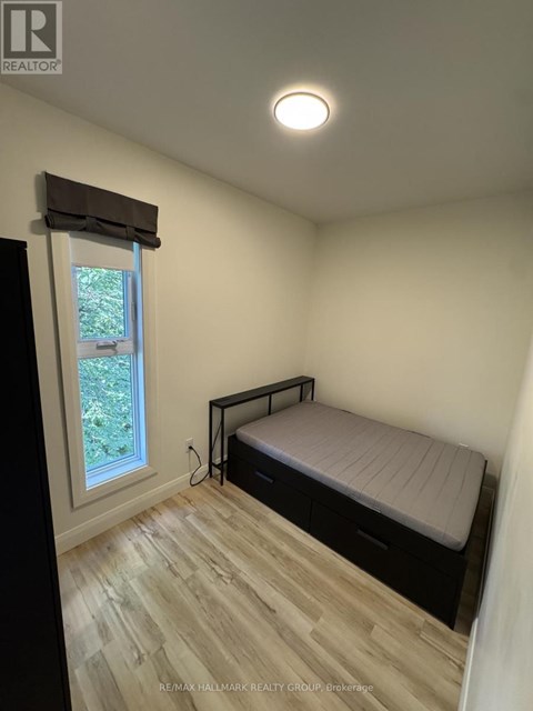 A bedroom with a bed, window, and wooden flooring.