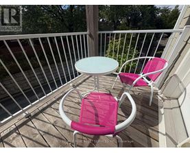 A white table and two pink chairs are on a deck.