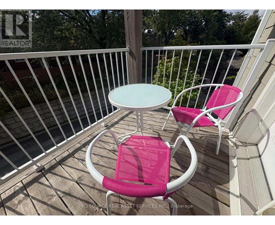 A white table and two pink chairs are on a deck.