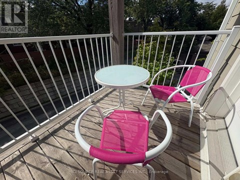 A white table and two pink chairs are on a deck.