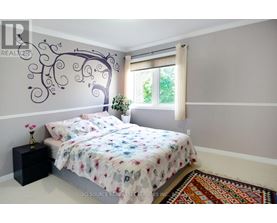 A bedroom with a large bed and a tree mural on the wall.