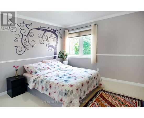 A bedroom with a large bed and a tree mural on the wall.