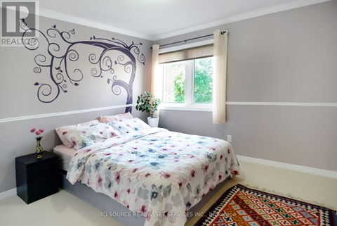 A bedroom with a large bed and a tree mural on the wall.