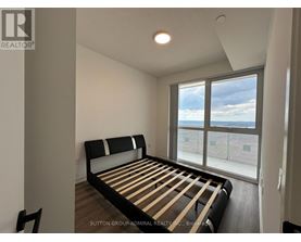 A bedroom with a large bed and a view of the outside through the window.