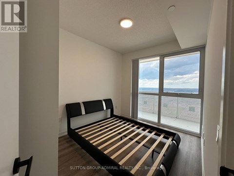 A bedroom with a large bed and a view of the outside through the window.