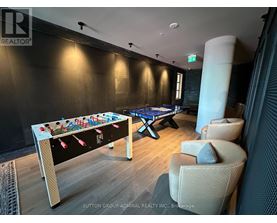 A pool table in a room with a foosball table and chairs.