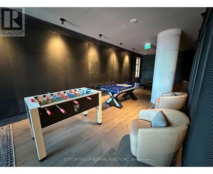 A pool table in a room with a foosball table and chairs.