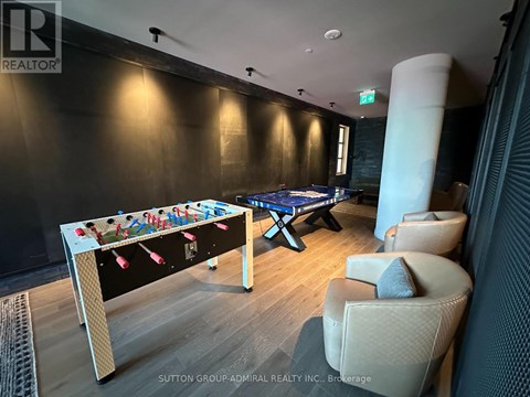 A pool table in a room with a foosball table and chairs.