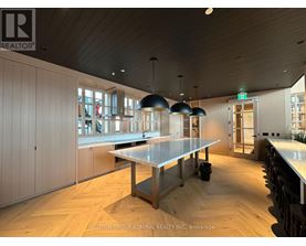 A modern kitchen with a long table and pendant lights.