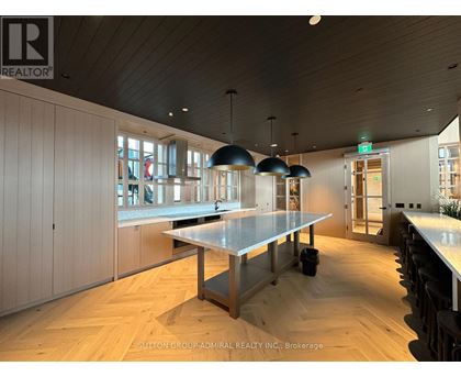A modern kitchen with a long table and pendant lights.