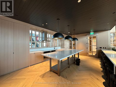 A modern kitchen with a long table and pendant lights.