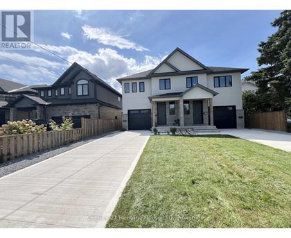 A large, modern house with a well-maintained lawn and a clear sky above.