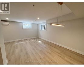 A spacious room with wooden flooring and a hanging light fixture.