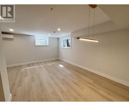 A spacious room with wooden flooring and a hanging light fixture.