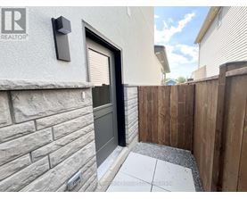 A grey house with a black door and a wooden fence.