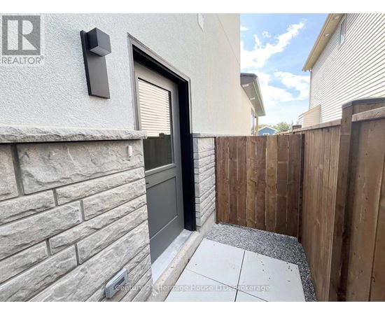 A grey house with a black door and a wooden fence.