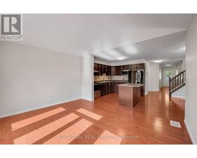 A spacious room with wooden floors and a staircase leading to another room.
