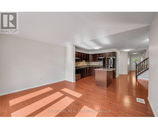 A spacious room with wooden floors and a staircase leading to another room.