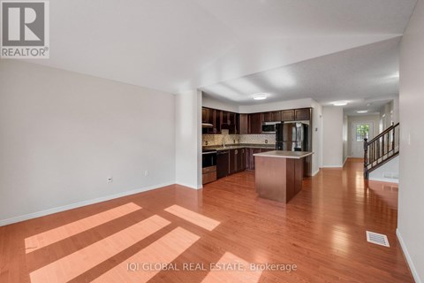 A spacious room with wooden floors and a staircase leading to another room.