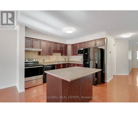 A kitchen with wooden cabinets and a black refrigerator.