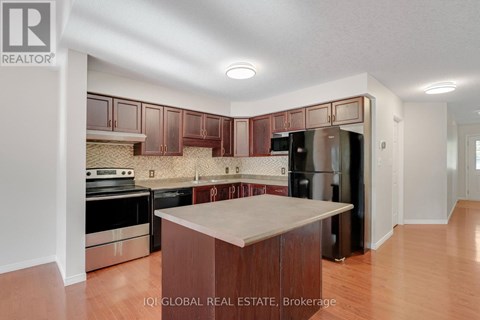 A kitchen with wooden cabinets and a black refrigerator.