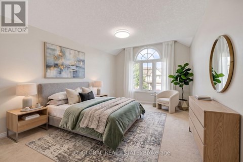 A bedroom with a large bed, a chair, and a painting on the wall.