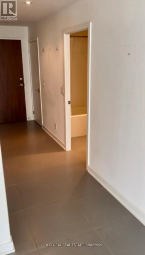 A hallway with a white door on the right and a brown door on the left.