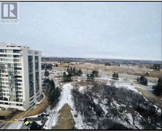 A view of a snowy landscape with a building on the left and a road in the middle.