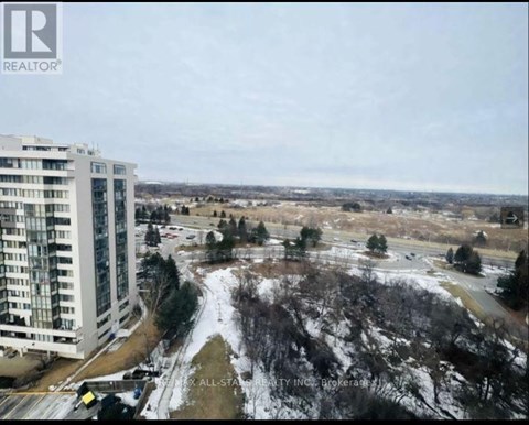 A view of a snowy landscape with a building on the left and a road in the middle.