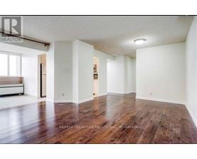 A large empty room with wood flooring and white walls.