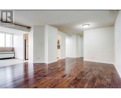 A large empty room with wood flooring and white walls.