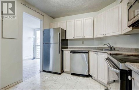 A kitchen with white cabinets and a stainless steel refrigerator.