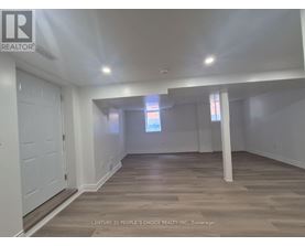 A spacious room with wooden flooring and white walls.